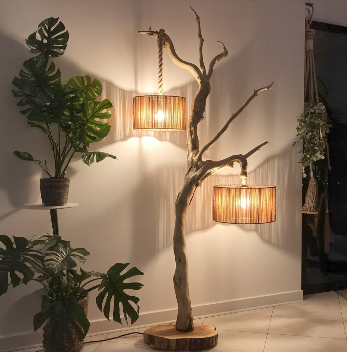 Rustic wooden tree lamp with two hanging warm light shades in modern minimalist room with green plants