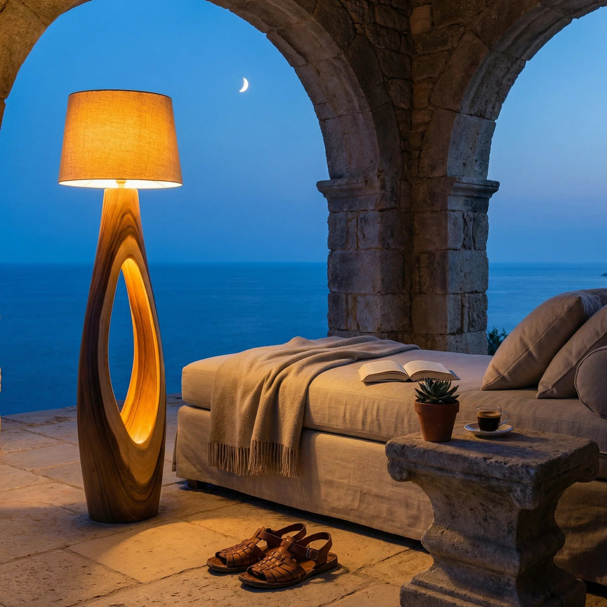 Terrasse einer Mittelmeer-Villa in der Dämmerung mit moderner Holzlampe, Lounge-Sofa und Meerblick.