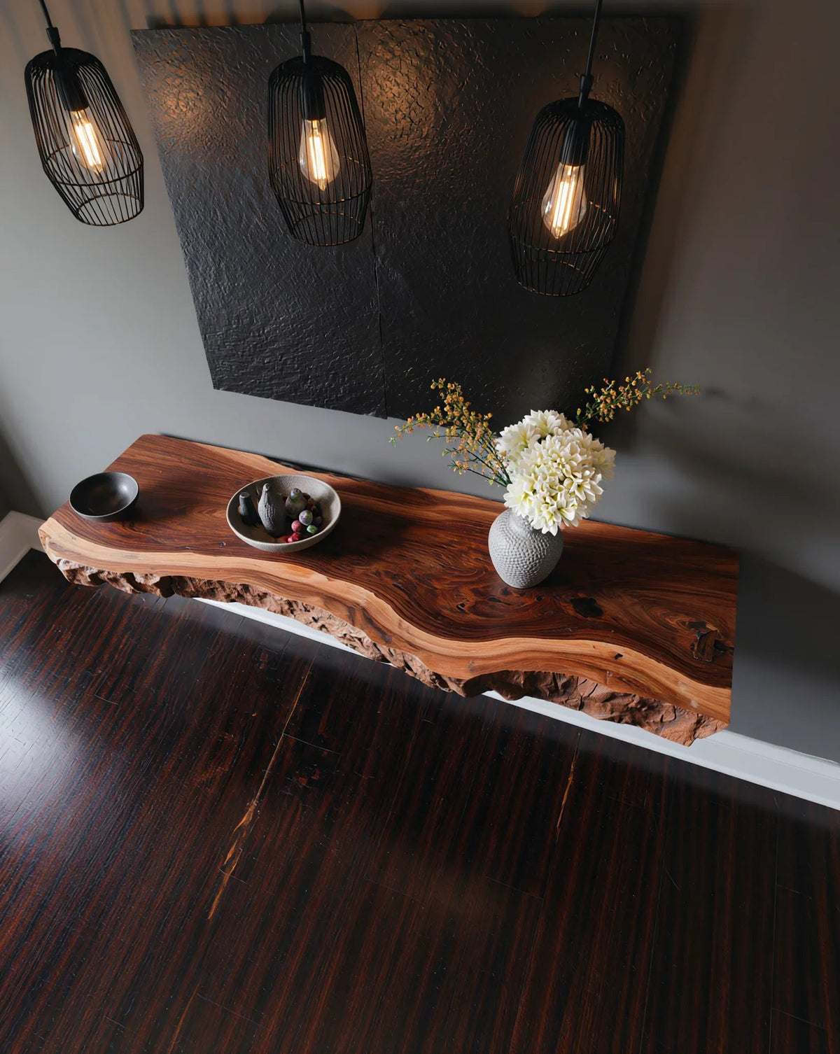 Baumkanten-Konsolentisch aus Holz mit Keramikvase, modernen Pendelleuchten und dekorativer Schale