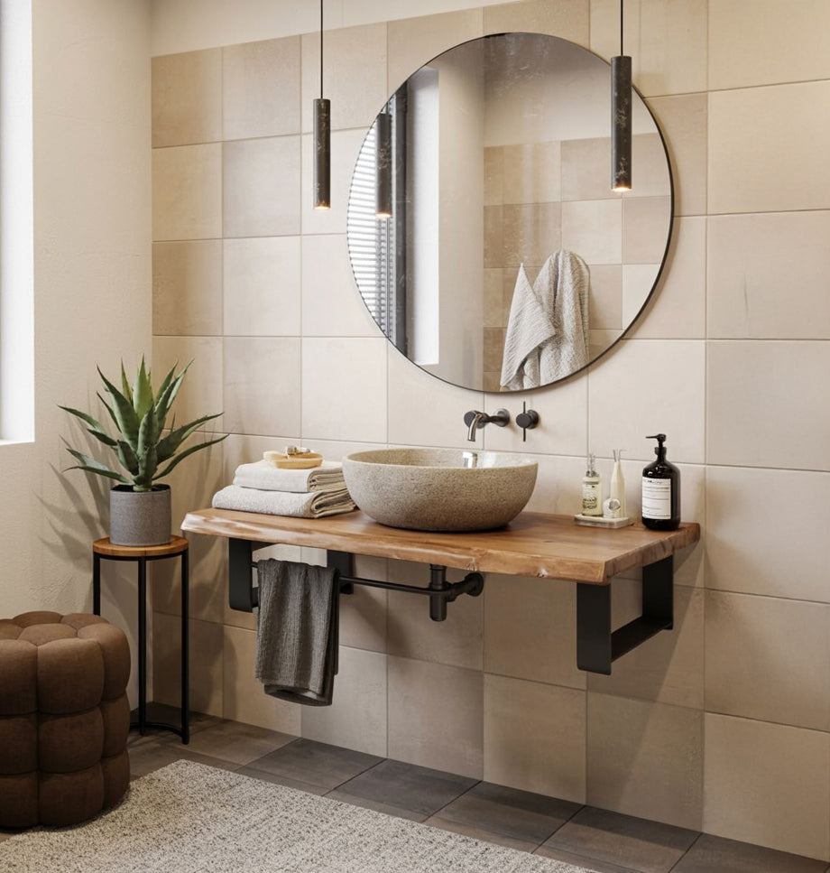 Modern bathroom with round mirror, stone vessel sink on wooden countertop, pendant lights, and plant