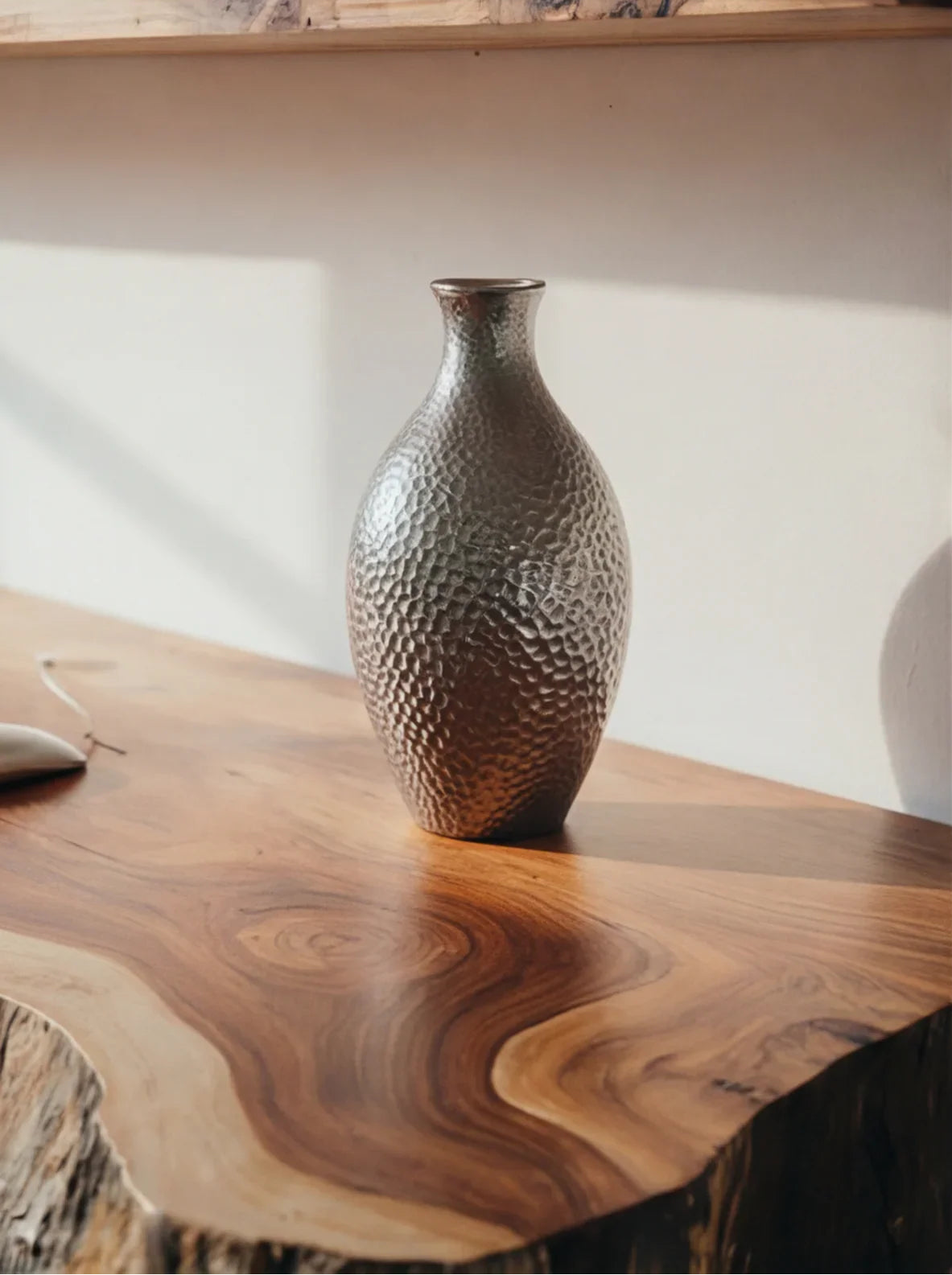 Strukturierte Metallvase auf einem Baumkanten-Tisch aus Massivholz mit natürlichem Maserungsmuster