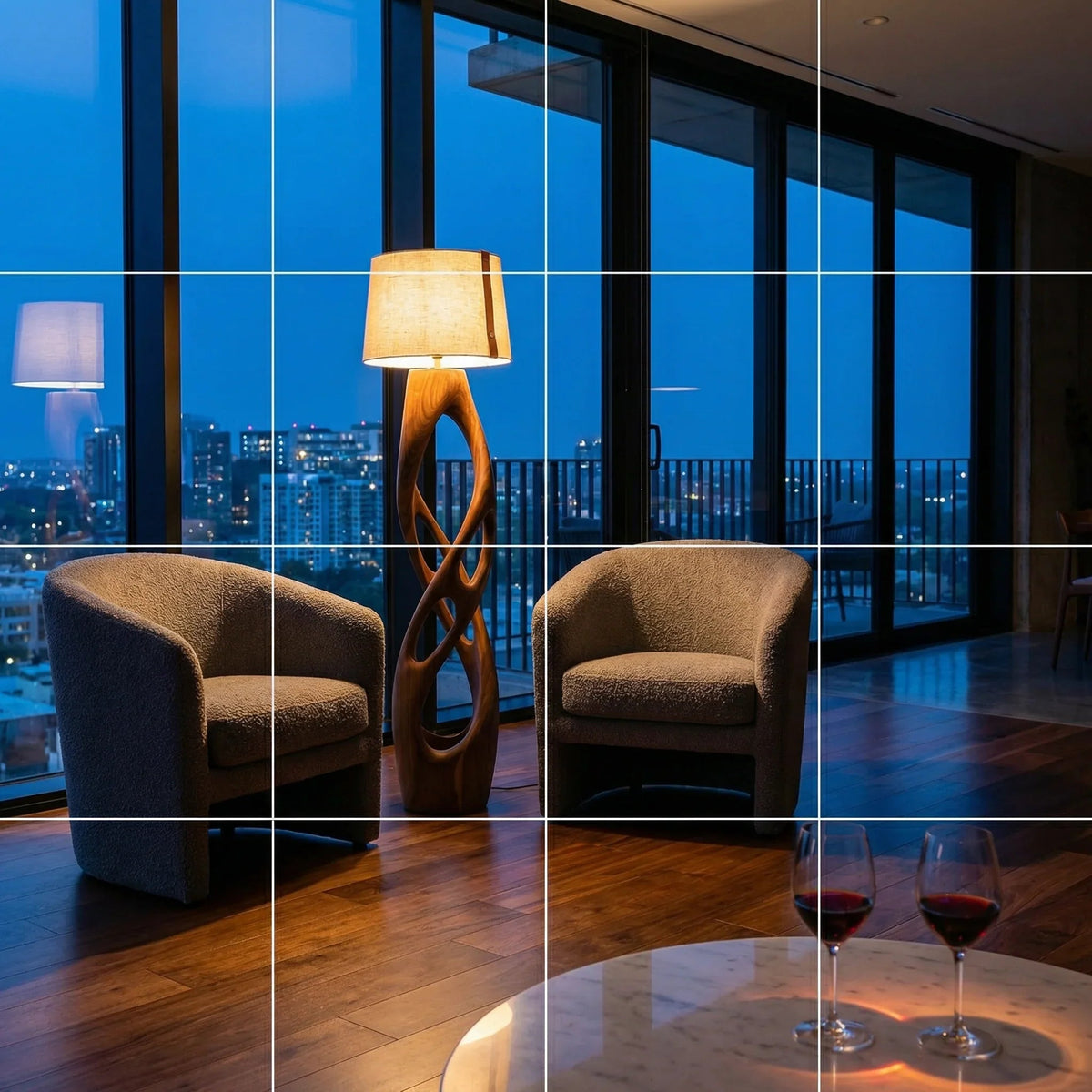 Modernes Penthouse-Wohnzimmer mit Stadtblick, zwei Sesseln, skulpturaler Holzlampe und Weingläsern