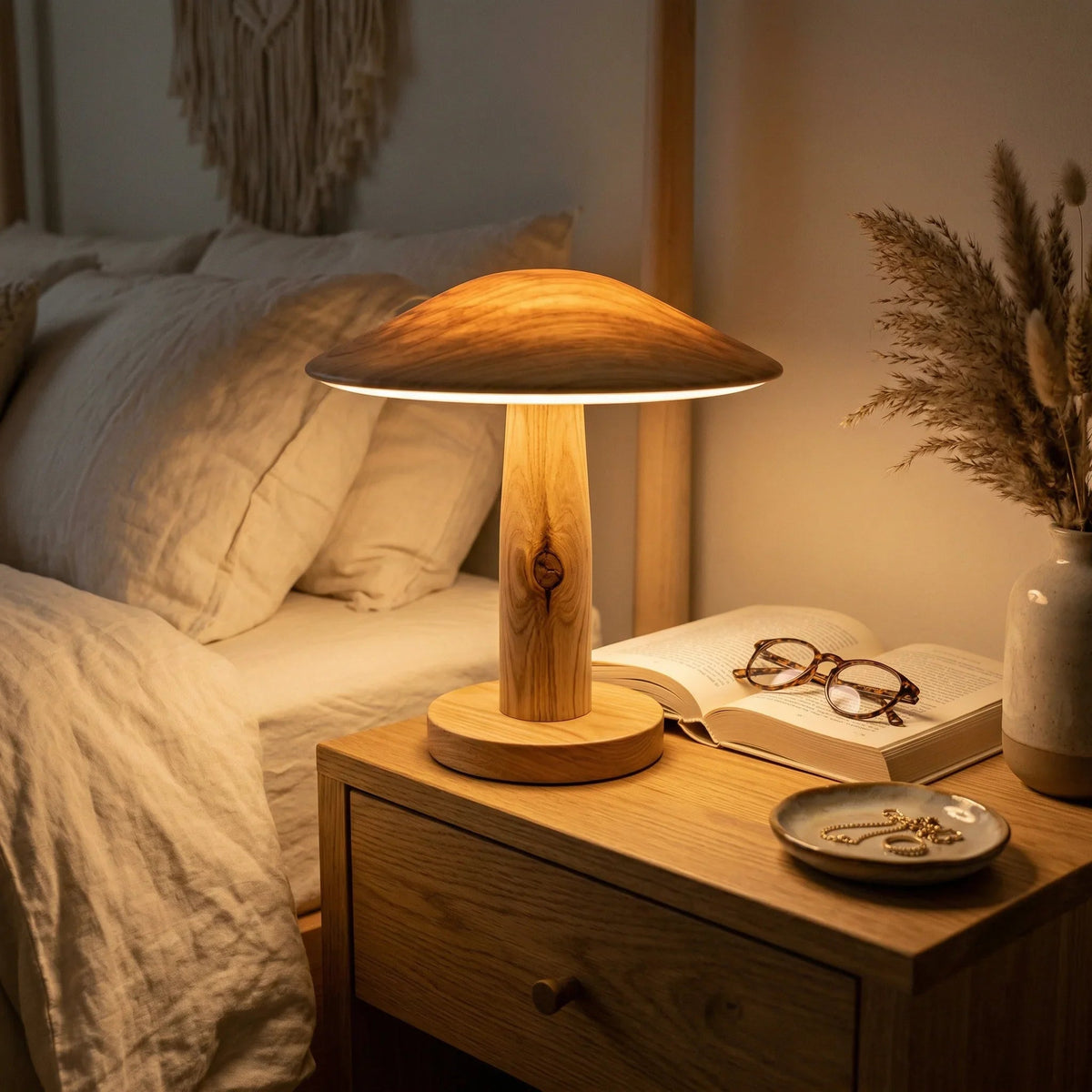 Modernes Boho-Schlafzimmer mit Holzlampe auf dem Nachttisch, aufgeschlagenem Buch und gemütlichem Abendlicht