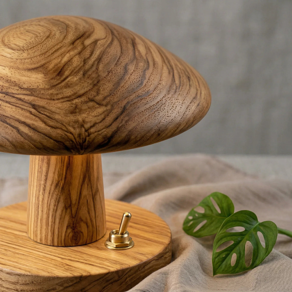 Nahaufnahme einer Pilz-Tischlampe aus Massivholz mit natürlicher Maserung, Messingschalter und Blattdekor